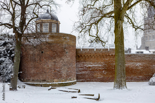 Snow landscape with architecture of city wall and Bourgonjetoren in the foreground and Walburgiskerk tower in the background during a snowstorm © Maarten Zeehandelaar