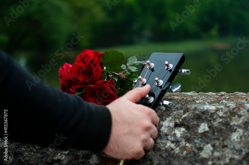 Man's hand holding guitar on the Roman Bridge