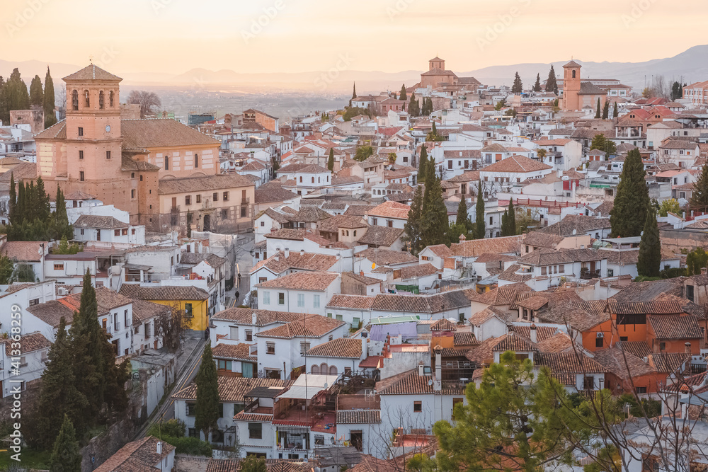 Old town sunset or sunrise cityscape view of terracotta rooftops and the Church of San Salvador in the historic Moorish or Arab Quarter (albaicin) in Granada, Andalusia, Spain.