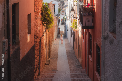 A young blonde female tourist exploring the narrow cobblestone backstreet of the old town  Albaicin or Arab Quarter  in Granada  Andalusia  Spain.