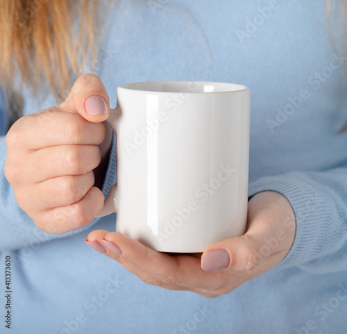 Female hands hold mock up white empty mug, cup for your design and logo closeup. Template blank for promotional text message or promotional content.