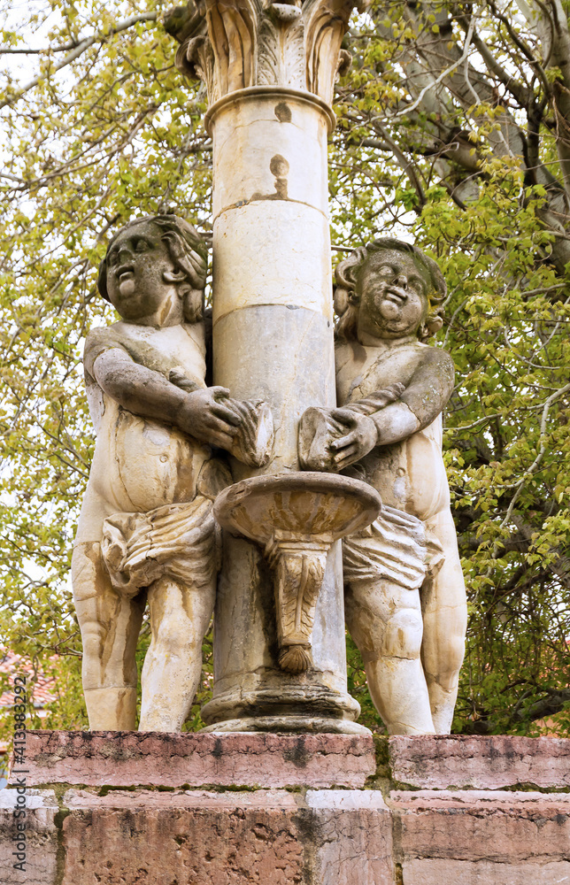 Figures of children in stone in column of public fountain. Plaza del Grano of Leon representing two rivers. Spain