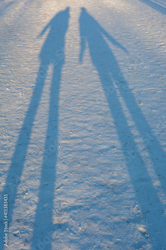 Canvastavla Along winter shadows in the snow of two people standing