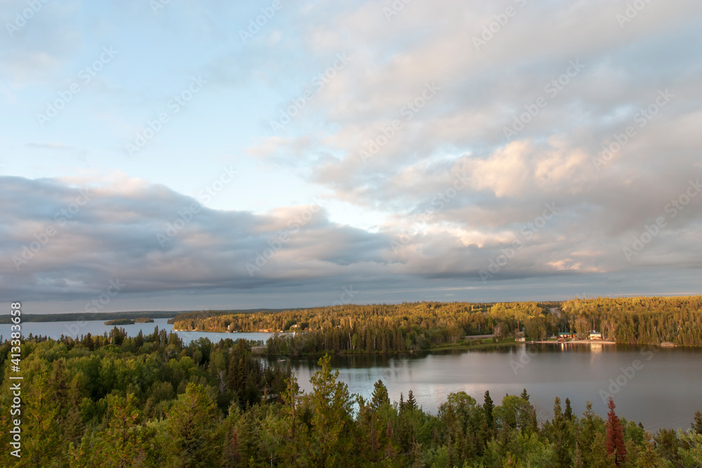 Panoramic view of peaceful lake scene with cabins surrounded by forrest.