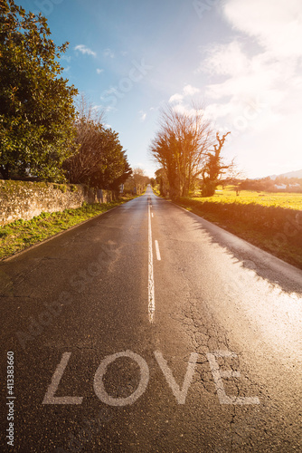 way to love. Road through fields where the word love is written on the asphalt. vertical stock image