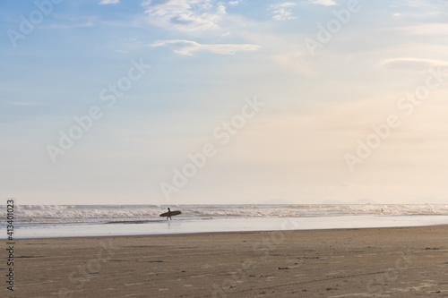 Surfista entrando no mar em praia vazia