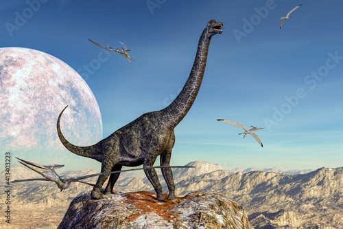 大きな月が浮かぶ青空を背景に荒野の岩山の頂上に佇むプラキオサウルスとその周りを飛ぶプテラノドン © iARTS_stock
