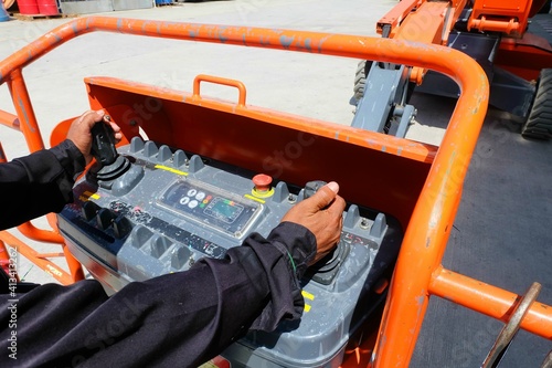 Workers are use control panel to driving the Orange articulate boom lift or telescopic boom lifts and bucket crane mounted on truck to safety for working at heights and articulating boom lift.