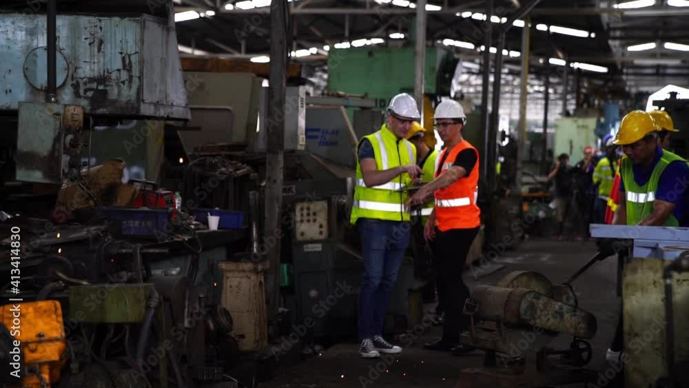 Workers wearing safety hat command machines in factory workshop. Asian mechanical engineer operating industrial lathe machine. Workers wearing safety hat command machines in factory workshop. Asian mechanical engineer operating industrial lathe machine.
