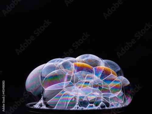 Abstract pattern from foam bubbles with rainbow gradient. Soap bubbles isolated on black background. Macro shot