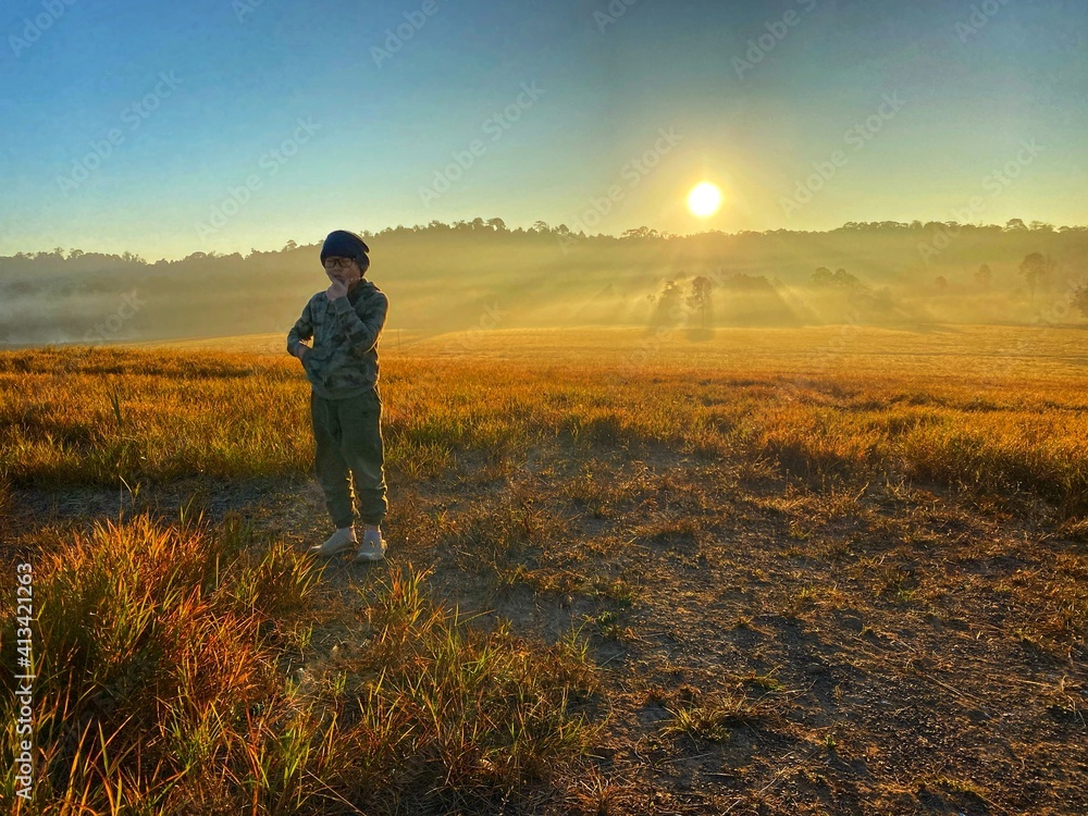 Asian boy  at the field while golden sky in the morning 