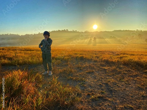 Asian boy at the field while golden sky in the morning 