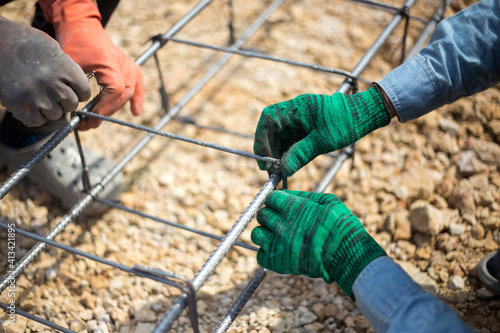 hands fixing steel reinforcement bars with officer