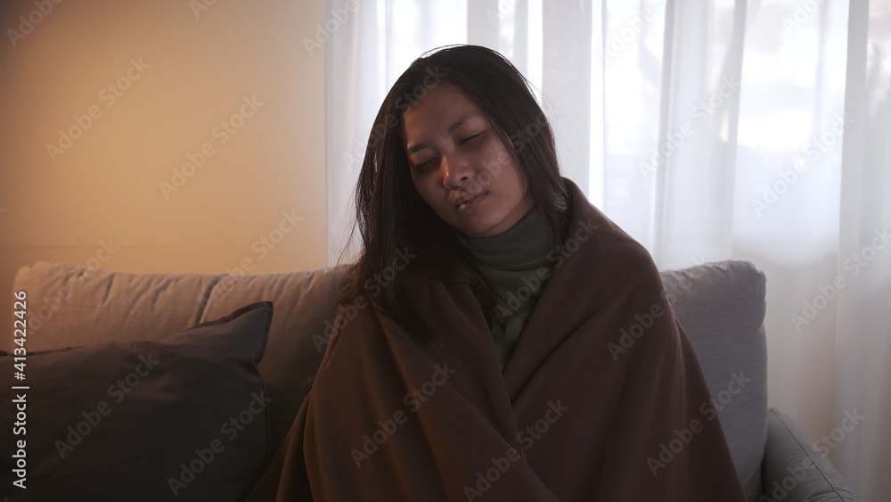 Young Asian woman with a black edge shakes her whole body is about to catch a cold and uses a blanket to keep warm on the sofa in the living room. Young Asian woman with a black edge shakes her whole body is about to catch a cold and uses a blanket to keep warm on the sofa in the living room.