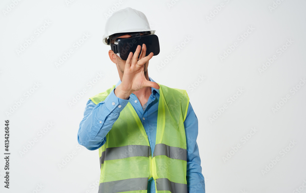 A man builder in a yellow vest and a white helmet with a roll of paper in his hand repairing work A man builder in a yellow vest and a white helmet with a roll of paper in his hand repairing work