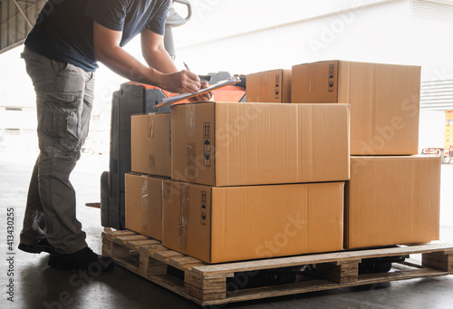 Warehouse worker holding clipboard his doing inventory management packaging boxes. Checking stock.  Shipment boxes. Shipping warehouse logistics photo