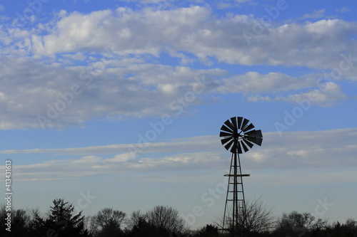 Kansas Windmill at Sunset with blue sky and white clouds north of Hutchinson Kansas USA out in the country.