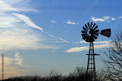 Kansas Windmill at Sunset with blue sky and white clouds north of Hutchinson Kansas USA out in the country.