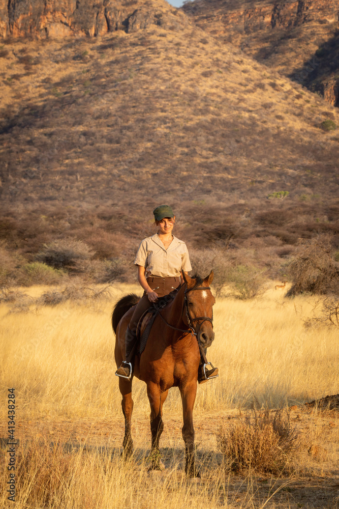 Smiling brunette on horseback with hills behind