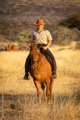 Smiling blonde on horseback with bushes behind © Nick Dale