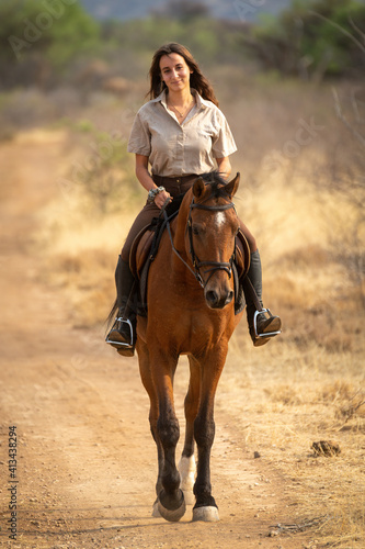 Smiling brunette rides horse on dirt track