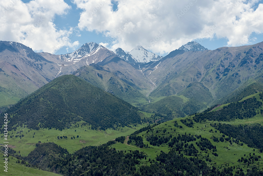 Obraz premium The nature of Kyrgyzstan. Mountain landscape. Among green valleys, mountains are visible at middle of the day. Tien Shan Mountains, Kyrgyzstan.