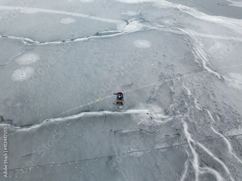 Fisherman on thin ice. Frosty drawing on ice. Aerial drone view. Winter cloudy morning.