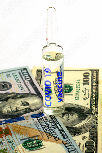 the concept of vaccination and business an ampoule with the inscription covid19 vaccine stands on banknotes on a white background