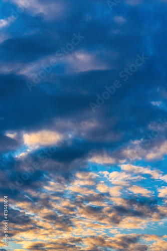Dramatic clouds in blue sky, illuminated by rays of sun at colorful sunset to change weather. Soft focus, motion blur summer cloudscape background. © Alexander Piragis