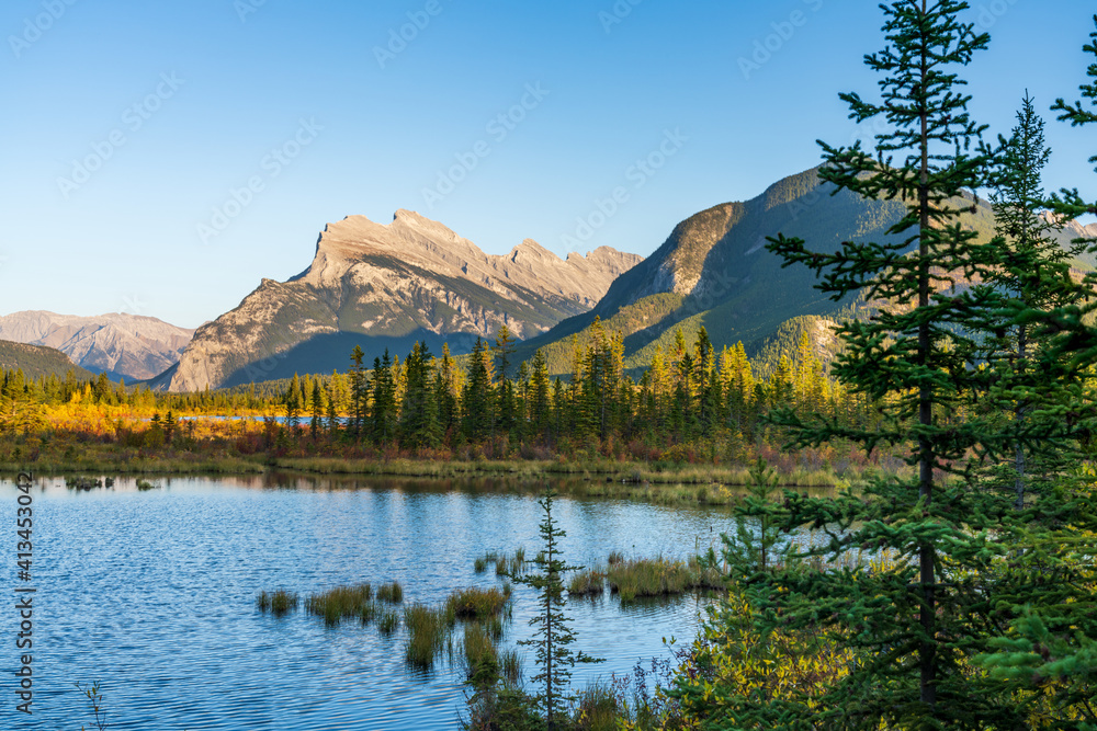 Vermilion Lakes autumn foliage scenery in dusk. Banff National Park, Canadian Rockies, Alberta, Canada. Colorful trees in orange, yellow, golden colors. Mount Rundle, Sulphur Mountain in background.