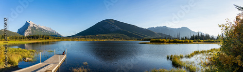 Vermilion Lakes panoramic view in autumn foliage season in sunset time. Banff National Park, Canadian Rockies, Alberta, Canada. Colorful trees and water plants with yellow, orange, golden colors.