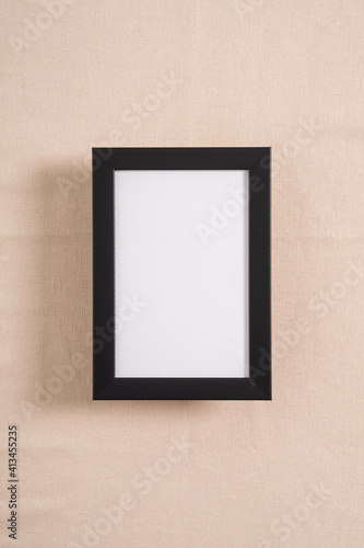 Black picture frame with white mockup on a beige textile