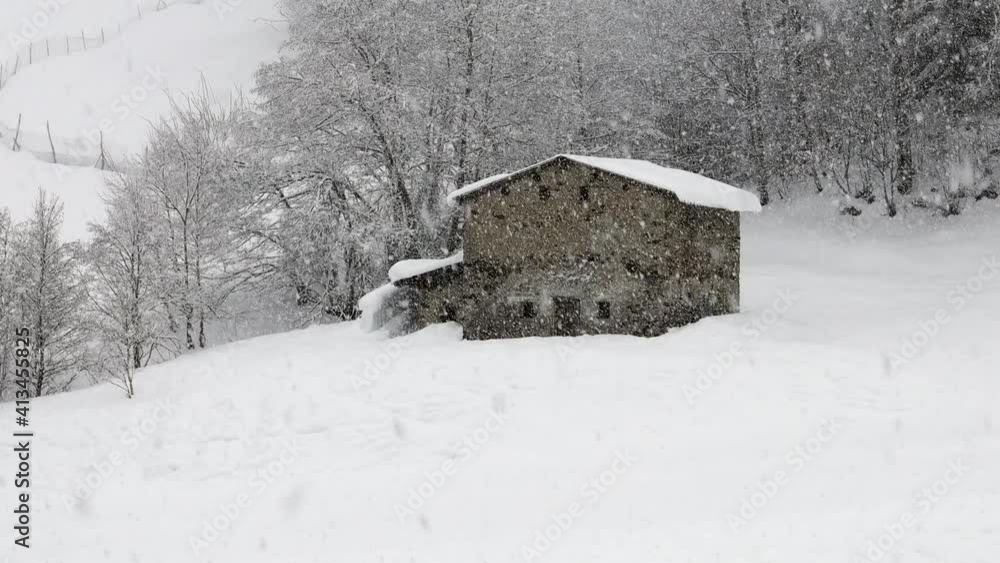 Zooming in, during a snowstorm, of an old abandoned stone house of the last century, standing still in the peace and the quiet. Valtellina region in Italy, Aprica ski area. Zooming in, during a snowstorm, of an old abandoned stone house of the last century, standing still in the peace and the quiet. Valtellina region in Italy, Aprica ski area.