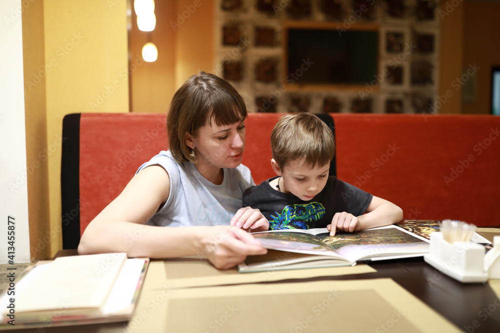 Mother with son examines magazine in cafe Mother with son examines magazine in cafe