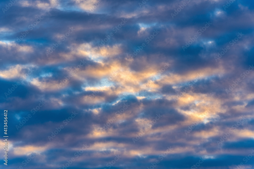 Beautiful clouds in blue sky, illuminated by rays of sun at sunset to change summer weather. Soft focus, motion blur multicolored cloudscape background.