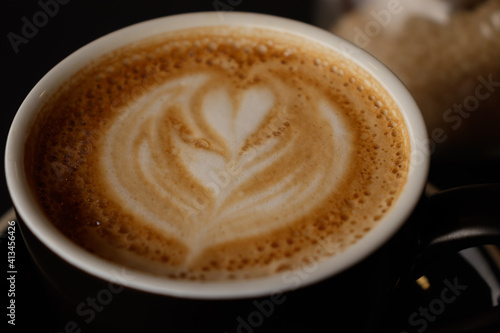 Flat white on a coffee cup with heart-shaped flower drawn with milk foam. For use as background with selective focus