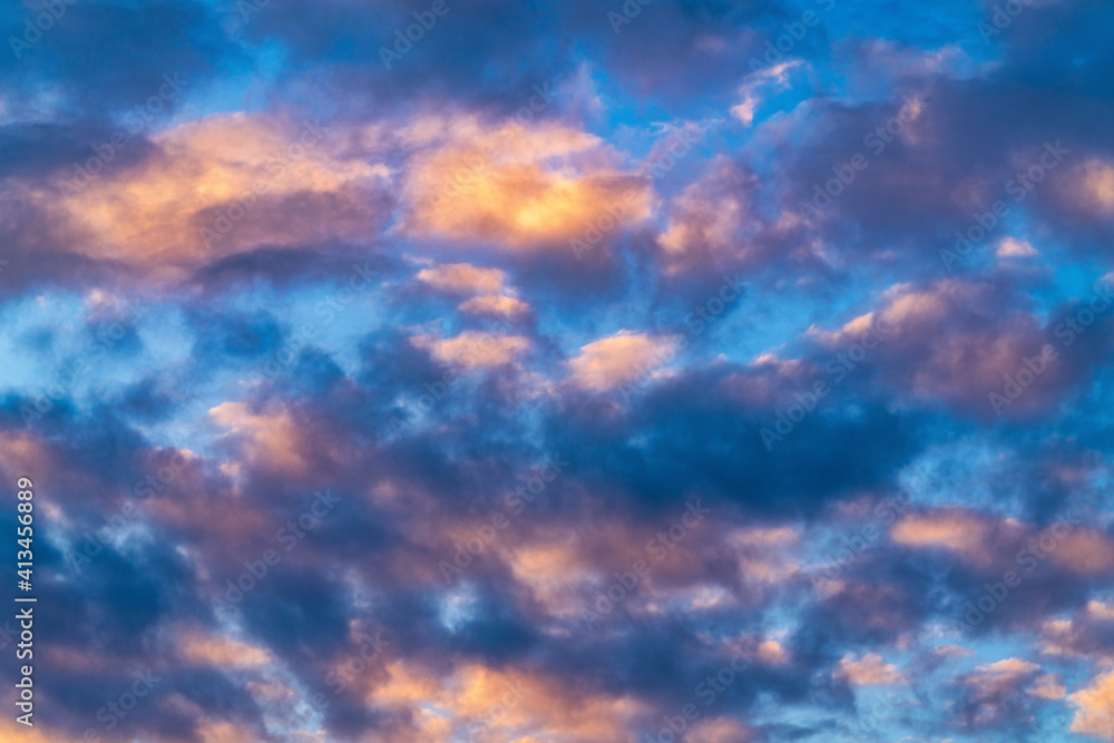 Beautiful clouds in blue sky, illuminated by rays of sun at colorful sunset to change weather. Soft focus, motion blur summer cloudscape background.