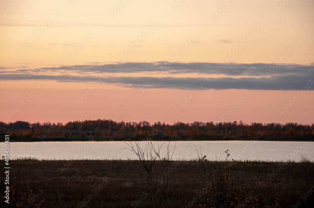 Sundown and sunrises. Blue sky with tints of purple and much clouds. Silhouettes of trees and grass are reflectioning in the river water. Background of heaven. Beautiful evening Sundown and sunrises. Blue sky with tints of purple and much clouds. Silhouettes of trees and grass are reflectioning in the river water. Background of heaven. Beautiful evening