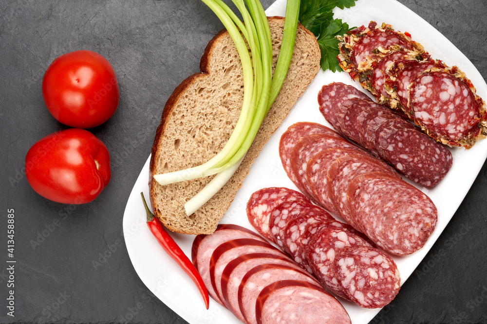 Smoked sausage slices on a white dish with a piece of black bread and onions. Vegetable and meat still life. Smoked sausage slices on a white dish with a piece of black bread and onions. Vegetable and meat still life.