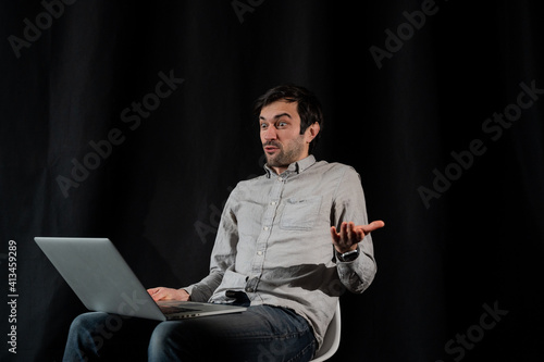 Pleasant positive business man using laptop.Happy smiling man in shirt works on laptop on a dark background photo