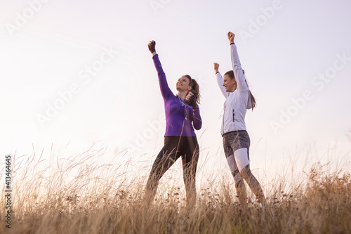 Young and happy best female friends in sportswear making high five together after successful training in nature