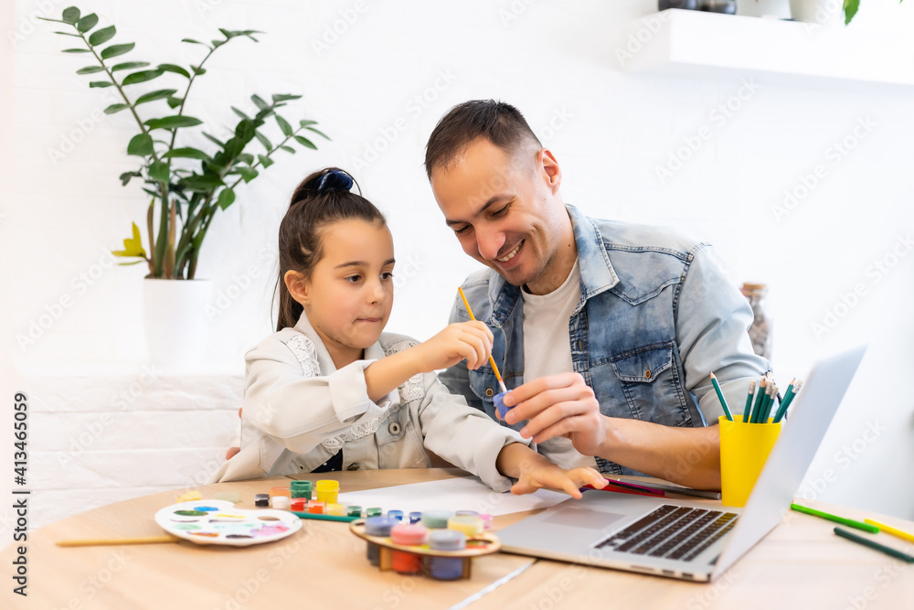 Young father helping her daughter with her school project on laptop at home Young father helping her daughter with her school project on laptop at home