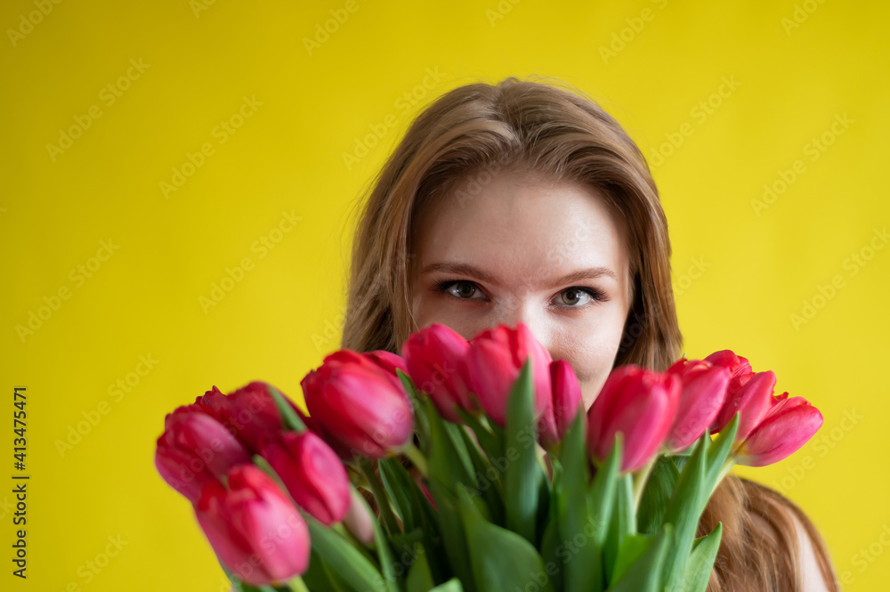 Woman with a bouquet of red tulips on a yellow background. Happy girl in a black dress holds an armful of flowers . Gift for Valentine's Day. The most romantic day of the year. Woman with a bouquet of red tulips on a yellow background. Happy girl in a black dress holds an armful of flowers . Gift for Valentine's Day. The most romantic day of the year.