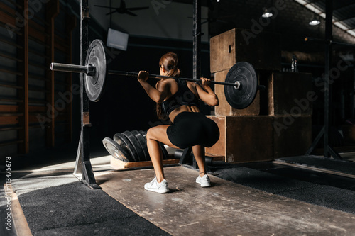 Fit young woman at a crossfit style on dark gray background. Fitness, functional, training, and lifestyle concept