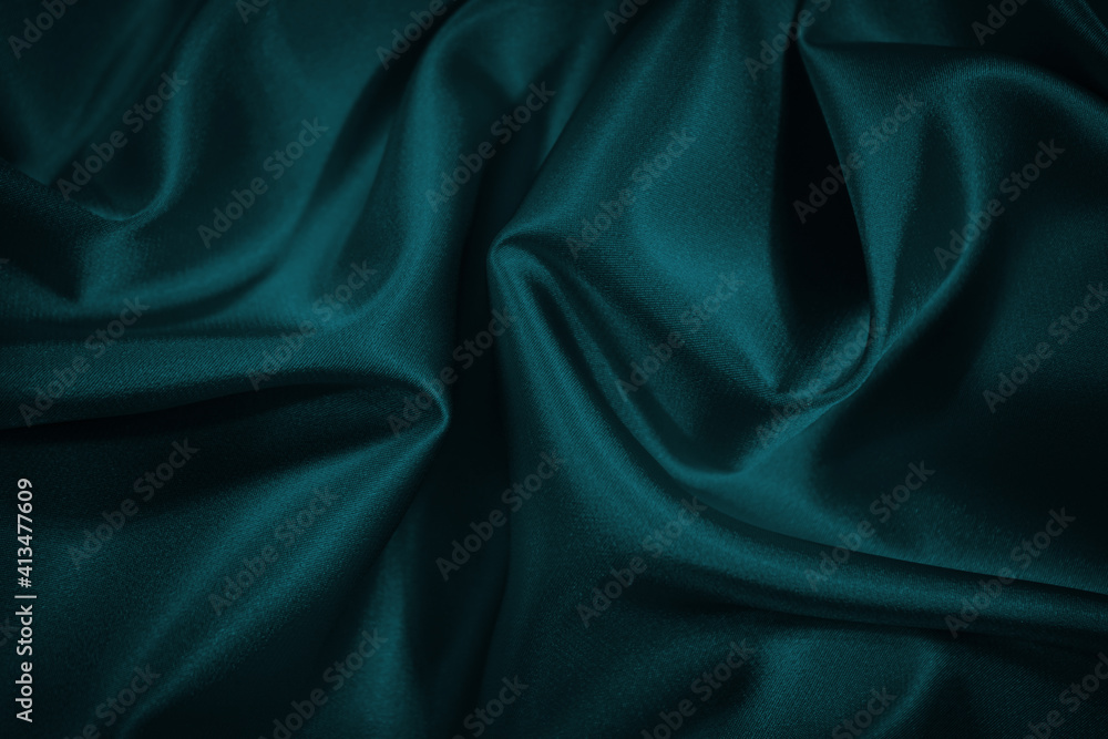 Obraz premium Black blue green abstract background. Dark green silk satin texture background. Beautiful wavy soft folds on the surface of the fabric. Teal elegant background with copy space for design. Web banner.
