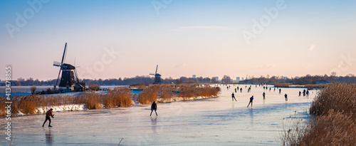 Classic Dutch scene with ice skaters on a lake during a cold period in winter.