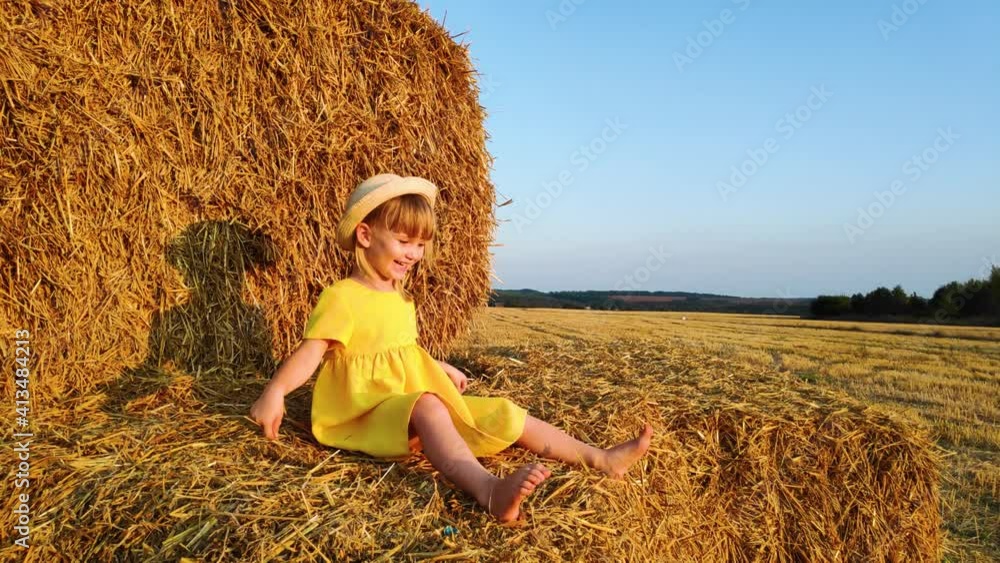 Happy little girl sits on haystack and laugh. Happy little girl sits on haystack and laugh.
