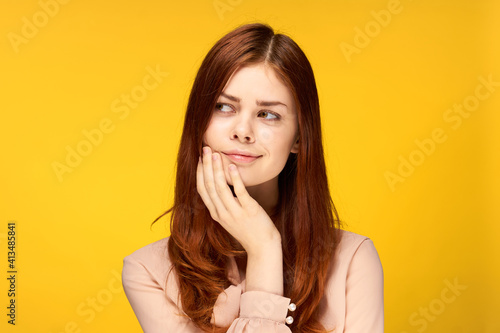 attractive woman holding hand near face charm emotion yellow background