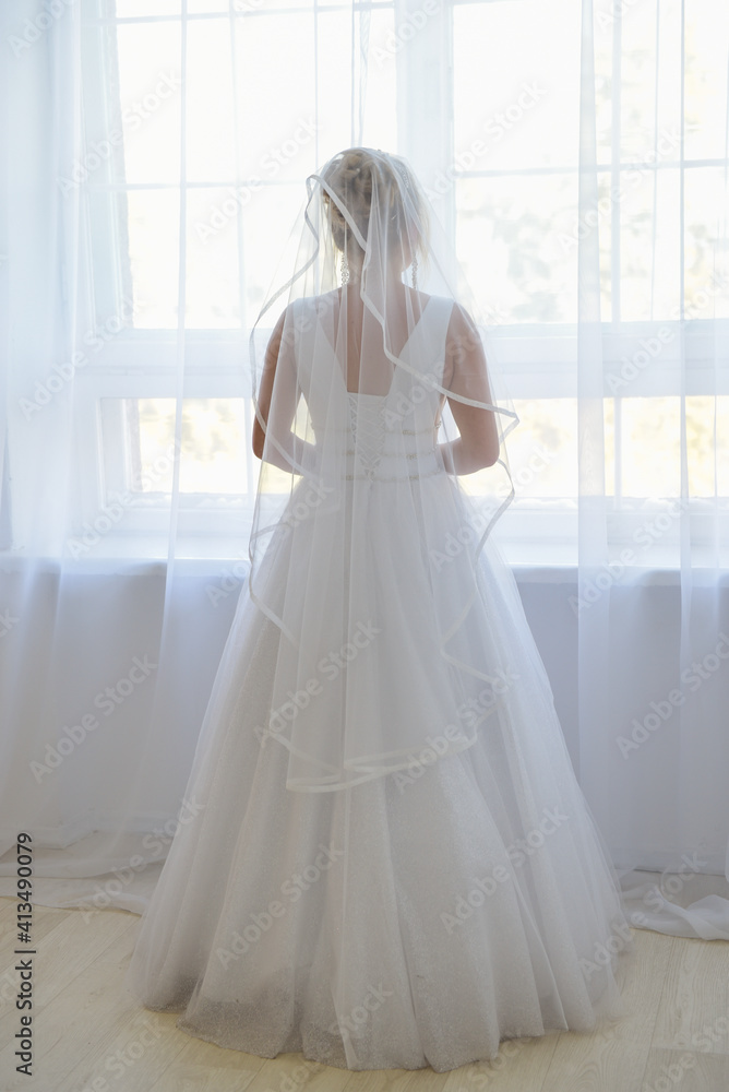 Bride in a apartment in a wedding dress. Bride looks out of the window, wedding day.
Charming bride stand in front of window in a white wedding dress. Bride in a apartment in a wedding dress. Bride looks out of the window, wedding day.
Charming bride stand in front of window in a white wedding dress.