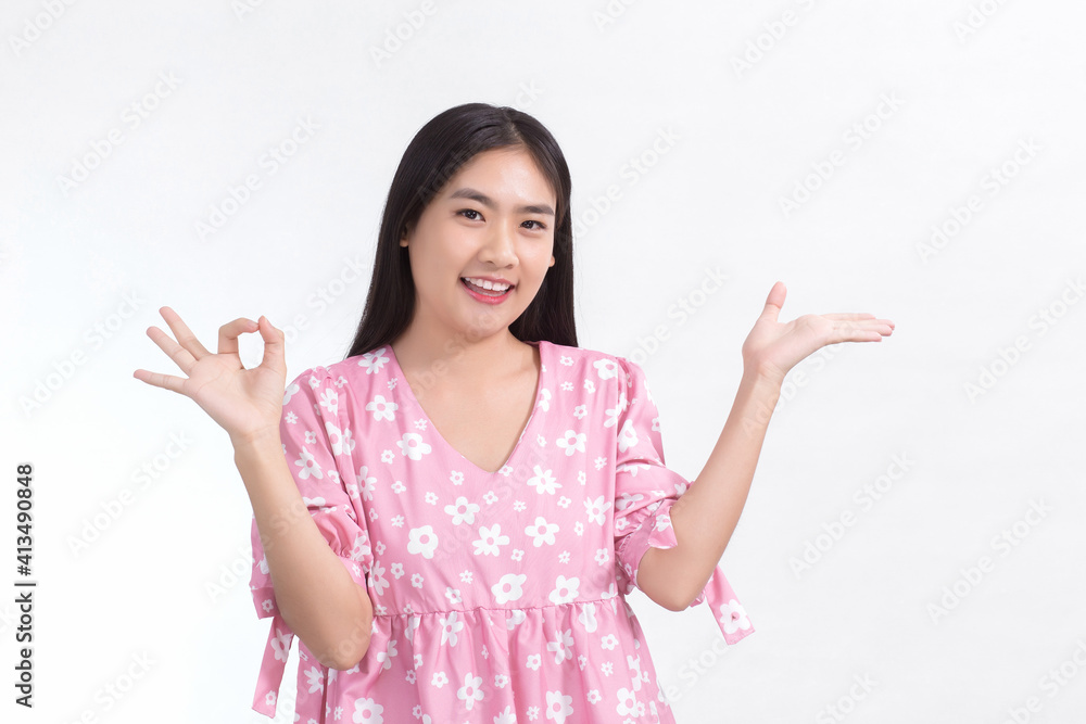 Asian woman with long black hair wears pink dress and shows hand “okey” sign on white background. Asian woman with long black hair wears pink dress and shows hand “okey” sign on white background.